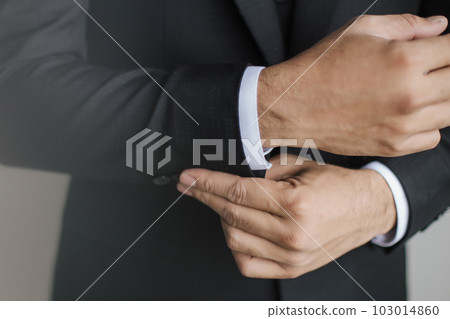 Close up preparation pose of a man fixing and a man holding buttons on sleeves suit and white shirt. 103014860