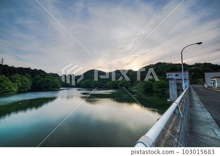 Evening view of Nunome Dam in early summer, beyond the dam, the setting sun reflected on the surface of the water 103015683