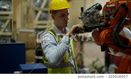 Maintenance engineer with robotic arms at industrial factory 103016957