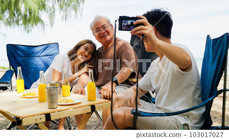 Happy Asian family with barbecue party at camping beach together Happy Asian family with barbecue party at camping beach together 103017027