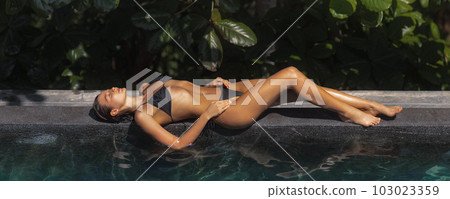 Bikini Model Relaxing in Infinity Swimming Pool at Luxury Villa Hotel in High-end Resort. Bikini Model Relaxing in Infinity Swimming Pool at Luxury Villa Hotel in High-end Resort. 103023359