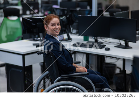 Caucasian smiling woman in wheelchair at work desk.  103025263