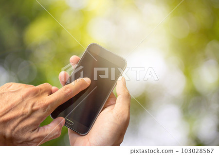 Close up of a man using mobile smart phone with outdoor green bokeh background Close up of a man using mobile smart phone with outdoor green bokeh background 103028567