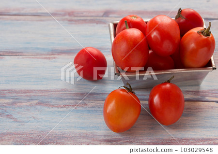 Close up red cherry plum tomatoes in stainless bowl on wood table background Close up red cherry plum tomatoes in stainless bowl on wood table background 103029548