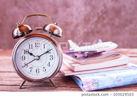 Retro alarm clock,airplane,map and notebook on a wooden table. 103029583