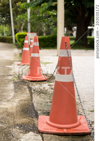 Close up bright orange traffic cones standing in a row on asphalt Close up bright orange traffic cones standing in a row on asphalt 103030172