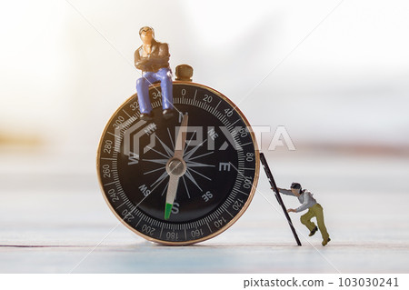 Miniature people- Figures businessman, is sitting on a compass area 103030241