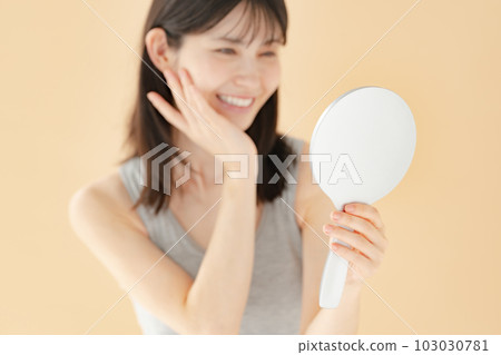 Woman checking with a hand mirror beauty 103030781