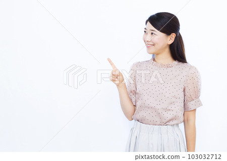 A woman in her thirties who raises her index finger in front of a white background 103032712