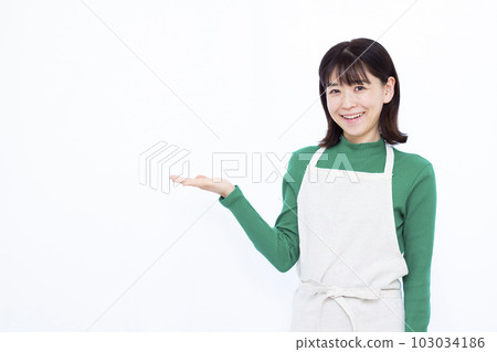 A housewife in her thirties making an introduction in front of a white background A housewife in her thirties making an introduction in front of a white background 103034186