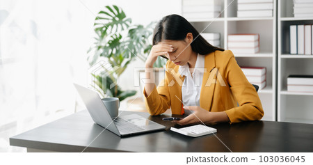 Asian business woman is stressed, bored, and overthinking from working on a tablet at the modern office.. 103036045