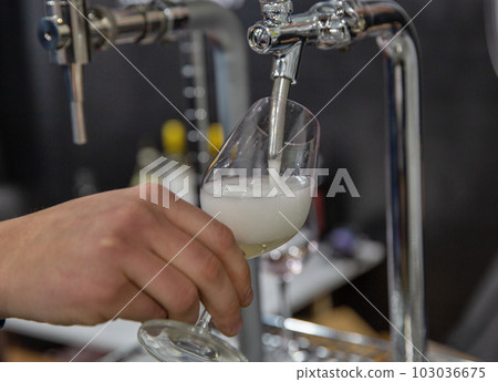 Pouring prosecco sparkling wine from a tap into a glass 103036675