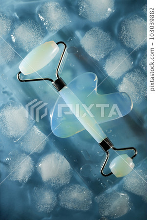 Blue jade face roller and Gua Sha scraping for beauty facial massage therapy on ice cubes and water background. Blue jade face roller and Gua Sha scraping for beauty facial massage therapy on ice cubes and water background. 103039882