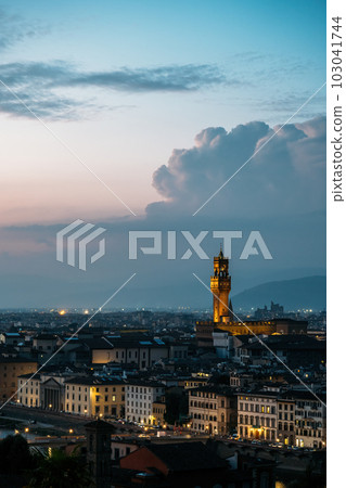 Vertical shot of Old Palace in Florence City Hall tower architect Arnolfo di Cambio in evening lights on warm summer with stunning cumulus clouds. Concept of outstanding architectural structures 103041744