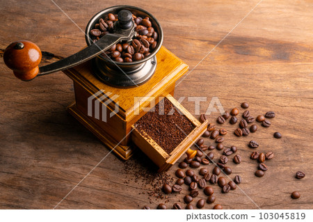 Vintage coffee grinder.Old retro hand-operated wooden and metal coffee grinder.Manual coffee grinder for grinding coffee beans on an old wooden background.selective focus, soft focus. 103045819