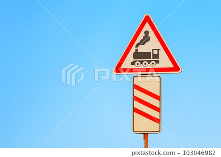 Level crossing warning sign on blue sky background. Railway transportation safety symbol. 103046982