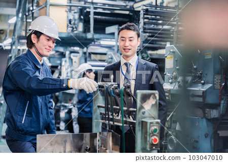 Salesman and worker talking in front of machine Salesman and worker talking in front of machine 103047010