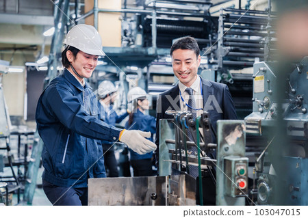 Salesman and worker talking in front of machine Salesman and worker talking in front of machine 103047015