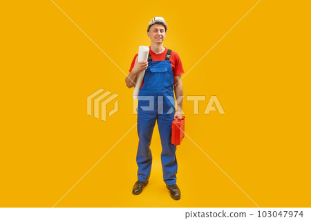 Young man engineer worker or architect with helmet holds documents blueprints and tool box. Isolated on yellow background. Copy space. Young man engineer worker or architect with helmet holds documents blueprints and tool box. Isolated on yellow background. Copy space. 103047974