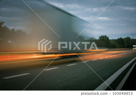 A truck driving on the highway at dusk. Motion blur on the highway. Evening shot of a truck. Concept of international transport and logistics. 103049853