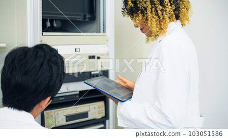 Multinational group operating electronic devices while looking at tablet Multinational group operating electronic devices while looking at tablet 103051586
