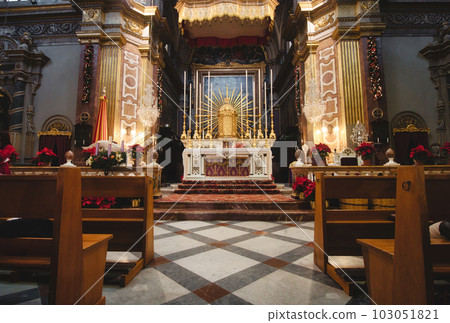 Front view of an altar in a large catholic church with wooden benches or pews 103051821
