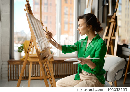 Woman painting brush on canvas at workshop during art lesson class 103052565