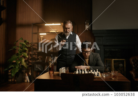 Two nervous chess players looking at chessboard over cozy home interior Two nervous chess players looking at chessboard over cozy home interior 103052638