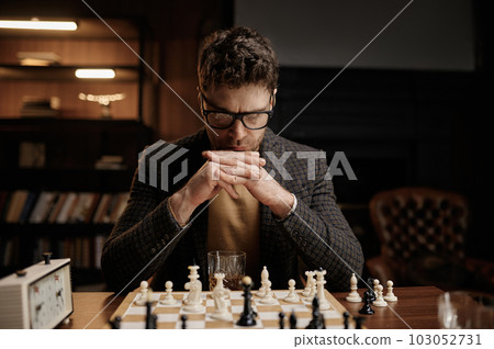 Focus on serious young man looking thoughtfully at chessboard pieces 103052731