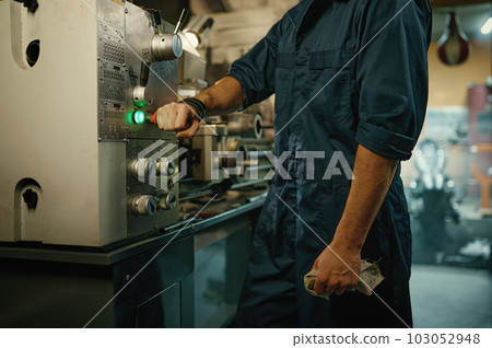 Closeup repairman hand turning off lathe machine with toggle switch 103052948