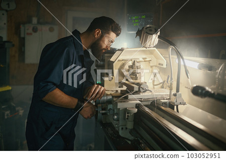 Serviceman working on turning lathe to adjust spare parts, repair work 103052951