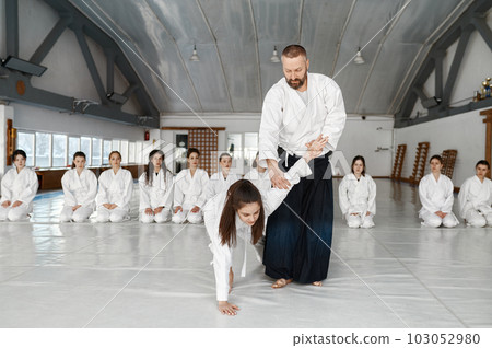 Aikido instructor teaching teenager fighters during group training in gym Aikido instructor teaching teenager fighters during group training in gym 103052980