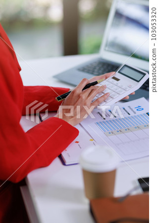 Concept of business office woman working,Businesswoman smile while working about her invesment plan with analyzing document and business investment graph data by using laptop on desk in workstation. Concept of business office woman working,Businesswoman smile while working about her invesment plan with analyzing document and business investment graph data by using laptop on desk in workstation. 103053320