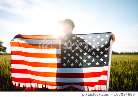 Man hold waving american USA flag. Patriot raise national american flag. Independence Day, 4th July. 103054699