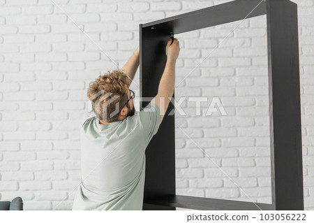 Portrait of man assembling furniture. Do it yourself furniture assembly at home 103056222