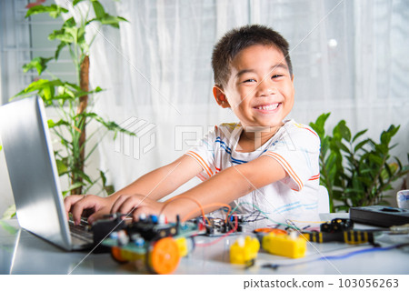 Asian kid boy learns coding and programming with laptop for Arduino robot car, Little child students typing code in computer online with car toy, STEAM education AI technology future course learning 103056263
