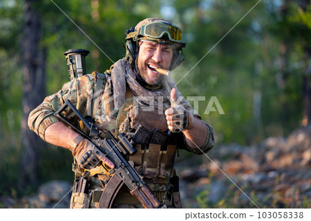 Smiling modern mercenary soldier smoking, smiling and showing thumb up. Smiling modern mercenary soldier smoking, smiling and showing thumb up. 103058338