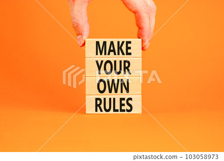Make your own rules symbol. Concept words Make your own rules on wooden cubes. Beautiful orange table orange background. Businessman hand. Business motivational make your own rules concept. Copy space Make your own rules symbol. Concept words Make your own rules on wooden cubes. Beautiful orange table orange background. Businessman hand. Business motivational make your own rules concept. Copy space 103058973