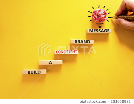 Consistent brand message symbol. Concept words build a consistent brand message on wooden blocks. Businessman hand. Beautiful yellow background. Business consistent brand message concept. Copy space. Consistent brand message symbol. Concept words build a consistent brand message on wooden blocks. Businessman hand. Beautiful yellow background. Business consistent brand message concept. Copy space. 103058981