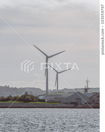 Wind power generators in the Ireland, landscape. Two wind turbines located in Ringaskiddy, County Cork. Cloudy overcast sky. wind turbine under cloudy sky Wind power generators in the Ireland, landscape. Two wind turbines located in Ringaskiddy, County Cork. Cloudy overcast sky. wind turbine under cloudy sky 103059797