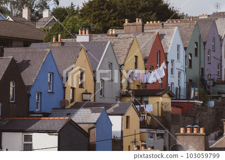 A row of colorful houses on the Irish city of Cobh, urban landscape. Cozy European architecture. The laundry is dried on a clothesline. A row of colorful houses on the Irish city of Cobh, urban landscape. Cozy European architecture. The laundry is dried on a clothesline. 103059799