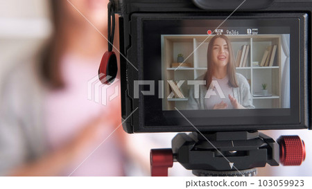 Online influencer. Live streaming. Woman blogger creating content shooting video for social media vlog using camera communicating with subscribers at home. Online influencer. Live streaming. Woman blogger creating content shooting video for social media vlog using camera communicating with subscribers at home. 103059923