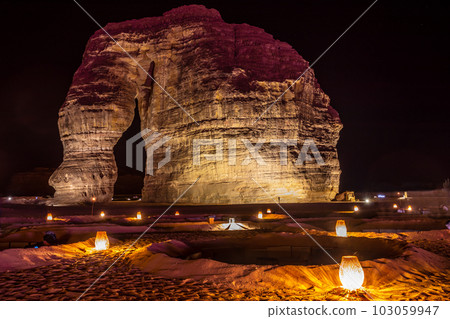 Illuminated outdoor lounge in front of elephant rock erosion monolith standing in the night desert, Al Ula, Saudi Arabia 103059947
