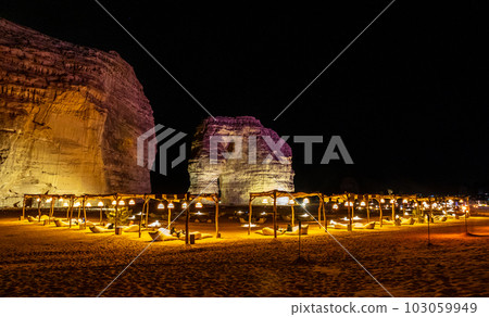 Illuminated outdoor lounge in front of elephant rock erosion monolith standing in the night desert, Al Ula, Saudi Arabia 103059949