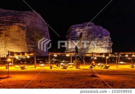 Illuminated outdoor lounge in front of elephant rock erosion monolith standing in the night desert, Al Ula, Saudi Arabia 103059950