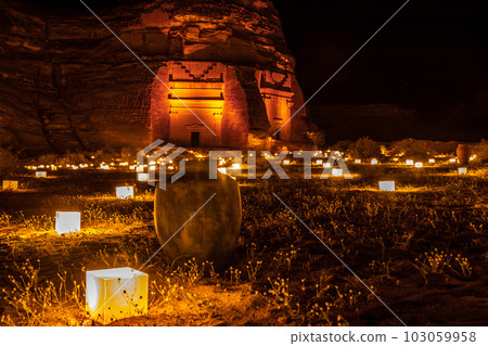 Old Amphora in front of ancient tombs of Hegra city illuminated during the night, Al Ula, Saudi Arabia 103059958