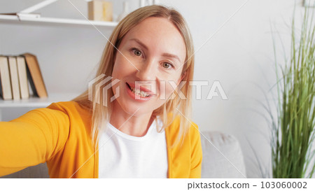 Video call. Online meeting. Distance communication. Friendly woman influencer making social media content broadcasting live stream in home interior. 103060002