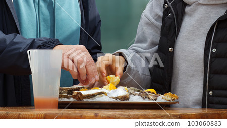 Eating oysters at a street food market. Eating oysters at a street food market. 103060883