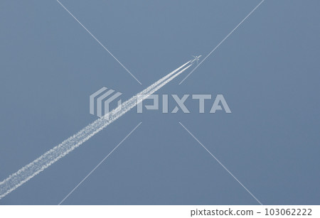 Contrails emanating from two jet engines (behind the wings) of an airliner flying in a clear blue sky Contrails emanating from two jet engines (behind the wings) of an airliner flying in a clear blue sky 103062222