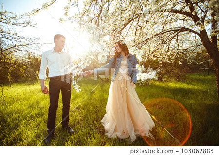 Beautiful loving couple in blooming gardens. Wedding concept. Great sunset light. Lovely newlyweds. 103062883